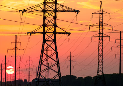Large metal poles transmission towers and power lines on the background of a red sunset