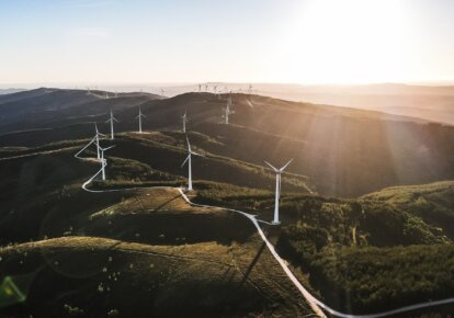 Wind turbines on rolling hills with sunlight